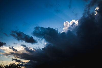 Low angle view of sunlight streaming through clouds