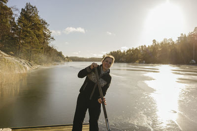 Smiling woman at lake using ice saw