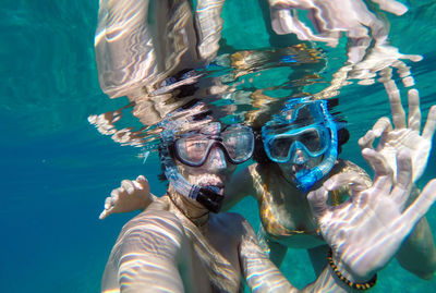 Couple showing ok sign while snorkeling in sea