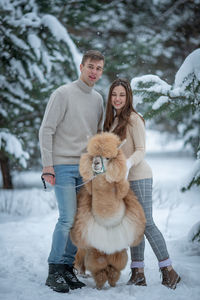 Portrait of smiling young woman with dog on snow
