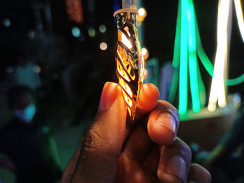 Close-up of hand holding illuminated candles