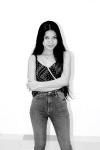 Portrait of a young woman standing against wall