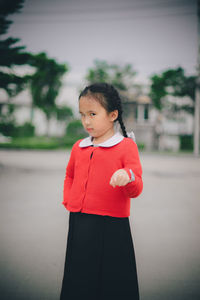 Portrait of cute girl pointing while standing on road