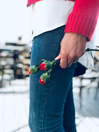 Midsection of woman holding red flower buds while standing outdoors