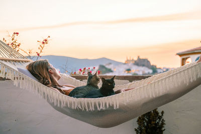 Midsection of woman resting against sky during sunset