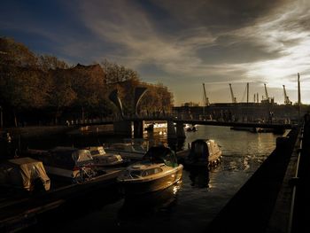 Boats in harbor against cloudy sky