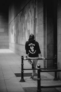 Man standing on footpath against wall