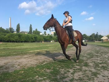 Teenage girl riding horse on field