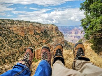 Low section of people relaxing at grand canyon national park against cloudy sky