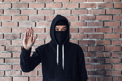 Portrait of man standing against brick wall