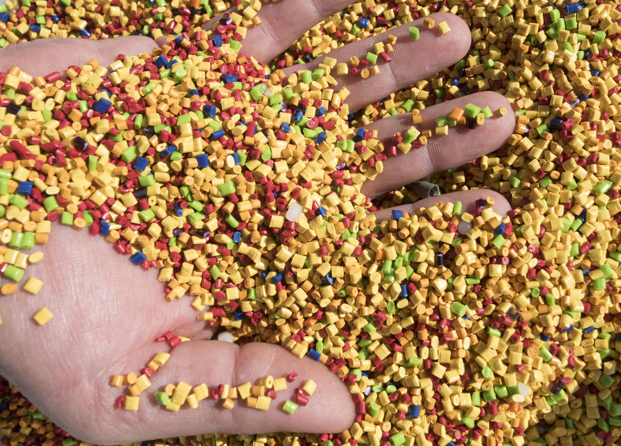 CLOSE-UP OF HUMAN HAND WITH MULTI COLORED CANDIES