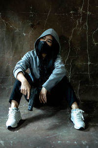 Full length of woman looking away while sitting on wall