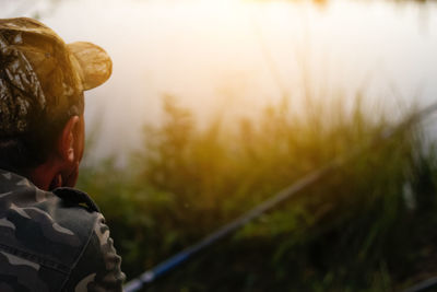 A man is engaged in fishing by a lake or pond, using a rod and spinning reel. he stands on the river