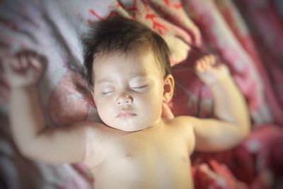 High angle view of shirtless baby boy sleeping on bed