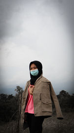 Young woman standing in snow against sky