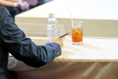 Midsection of man holding drink on table