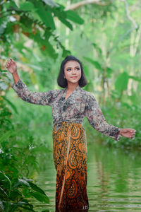 Portrait of young woman standing against plants