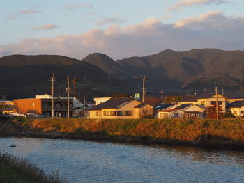 River by buildings and mountains against sky