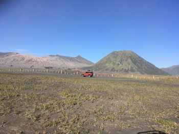 Scenic view of land and mountains against clear blue sky