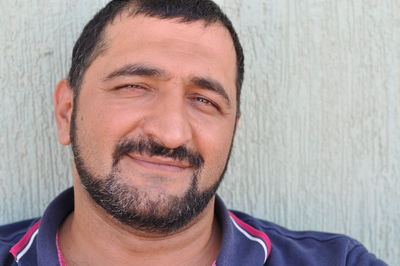 Close-up portrait of a smiling man against wall