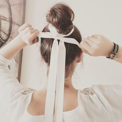 Rear view of bride tying ribbon on hair bun