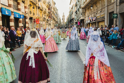 Rear view of people walking on street in city