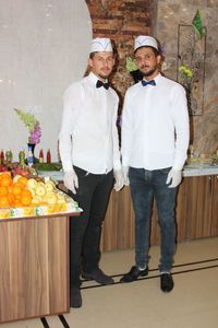 Portrait of friends standing by flowers