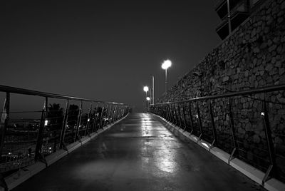 Illuminated footbridge against clear sky at night