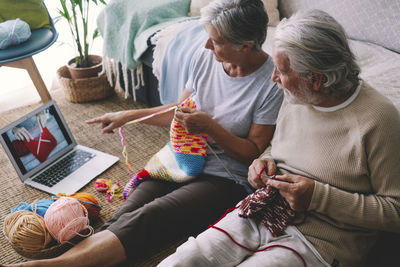 Woman watching knitting tutorial with man at home