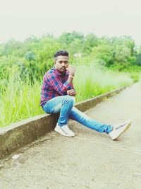 Side view of young man sitting on grass