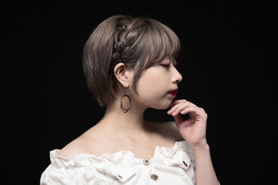 Portrait of a young woman looking away over black background