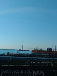 Bridge over sea against clear blue sky