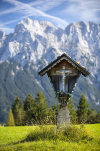 Crucifix on field against mountain