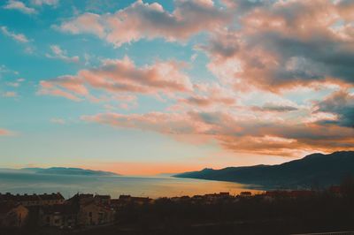 Silhouette houses in town against sky during sunset