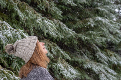 Woman standing against trees during snowfall