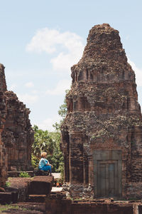 Side view of woman sitting at temple old ruin