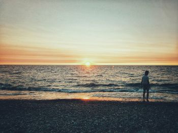 Silhouette man standing on beach against clear sky during sunset