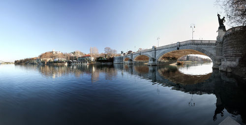 Bridge over river by buildings against sky