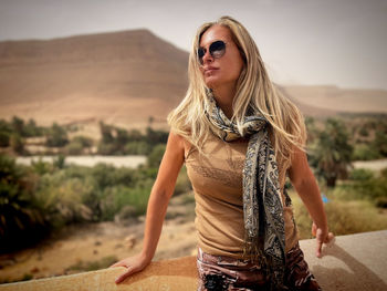 Portrait of young woman wearing sunglasses while standing against sky