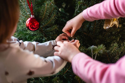 Children hands decorating christmas tree at home