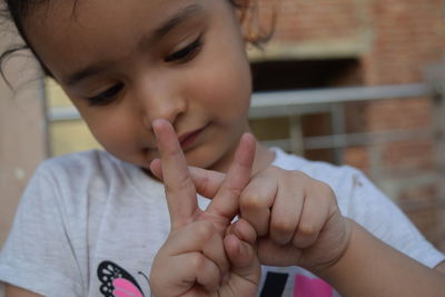 Close-up portrait of a girl making shapes with finger 