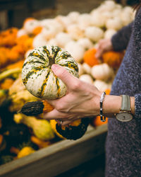 Midsection of woman holding pumpkin at market