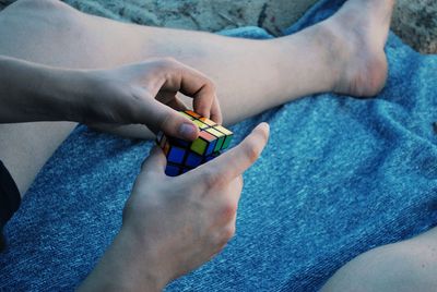 Low section of person playing with puzzle cube