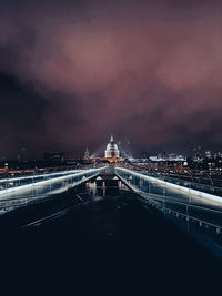 Illuminated bridge over river against sky at night