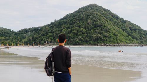 Rear view of man looking at sea against sky