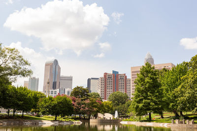 Trees and buildings in city against sky