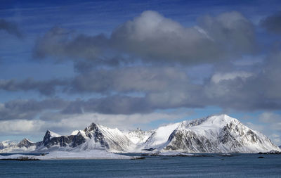 Scenic view of sea and snowcapped mountains against sky