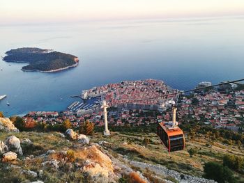 Cable car hanging over townscape against sea