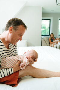 A father and newborn in the foreground with mother and toddler behind