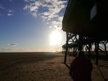 Rear view of silhouette man on beach against sky during sunset